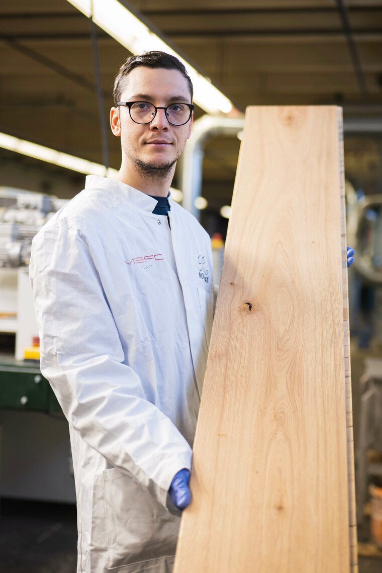 Mitarbeiter hält Diele zur Qualitätskontrolle